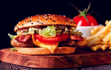 Tavuk pirzolası, kızarmış domuz pastırması ve sebzeli hamburger, patates kızartması, bir bardak bira, ahşap tahtada, insan yok, yatay.,