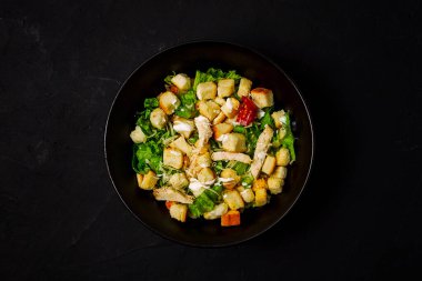 Taze geleneksel Sezar salatası, tavuklu, siyah arka planda, üst tarafta, koyu arka planda, yatay, hiç kimse yok.,