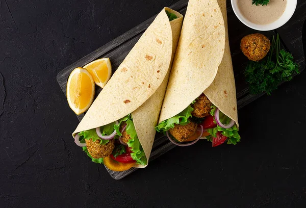 Tortillas avvolto con palline di falafel e verdure fresche, cibo sano vegetariano, su uno sfondo nero, nessuna gente, — Foto Stock