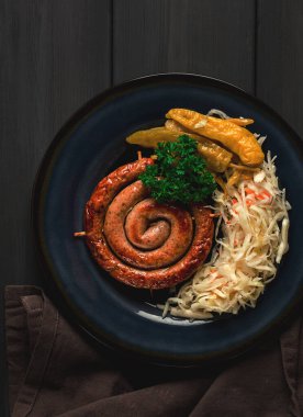 Geleneksel Alman yemeği, kızarmış sarmal sosis, lahana turşusu, kırmızı sos, koyu gri ahşap arka plan, üst manzara, yatay, insan yok.,