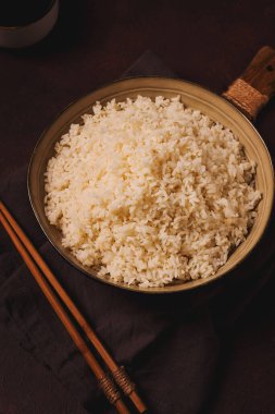 Bir tabak haşlanmış pirinç, ahşap sopalı, kahverengi arka planda, insan yok, seçici odaklı, tonlu..