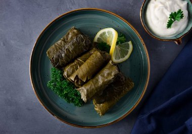 Dolma, lahana ruloları, dolgulu üzüm yaprakları, beyaz sos, limon ve otlar, kırsal, seçici odak, insan yok.,
