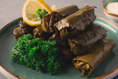Dolma, lahana ruloları, dolgulu üzüm yaprakları, beyaz sos, limon ve otlar, kırsal, seçici odak, insan yok.,