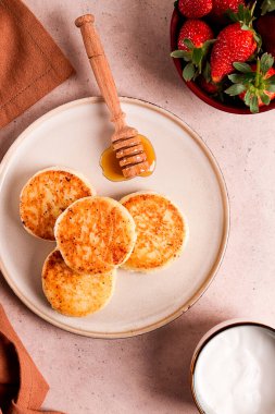 Beyaz soslu ve çilekli süzme peynir krepleri, bej bir masanın üstünde, üst manzara, seçici odak, insan yok.,