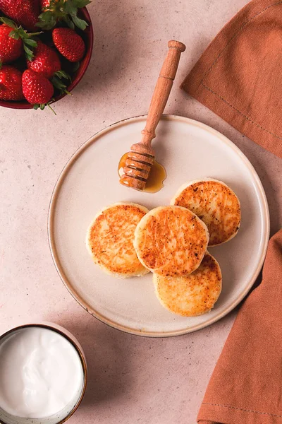 Beyaz soslu ve çilekli süzme peynir krepleri, bej bir masanın üstünde, üst manzara, seçici odak, insan yok.,