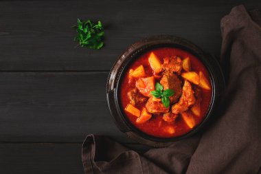 Patatesli, domates soslu, baharatlı ve otlu, yakın plan, insan yok, siyah arka planda.