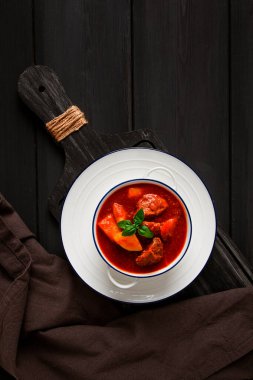 Patatesli, domates soslu, baharatlı ve otlu, yakın plan, insan yok, siyah arka planda.