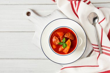 Etli, domates soslu, baharatlı ve otsuz patatesler beyaz bir masada.,