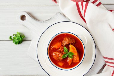 Etli, domates soslu, baharatlı ve otsuz patatesler beyaz bir masada.,