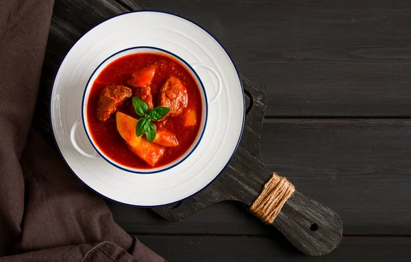 Patatesli, domates soslu, baharatlı ve otlu, yakın plan, insan yok, siyah arka planda.