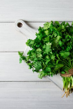 Bir grup taze Cilantro, beyaz ahşap bir masada, yakın plan, üst manzara, insan yok..