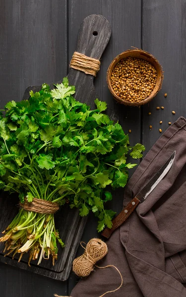 bunch of fresh Cilantro, coriander seeds, on a dark wooden table, close-up, top view, no people. food and drink,