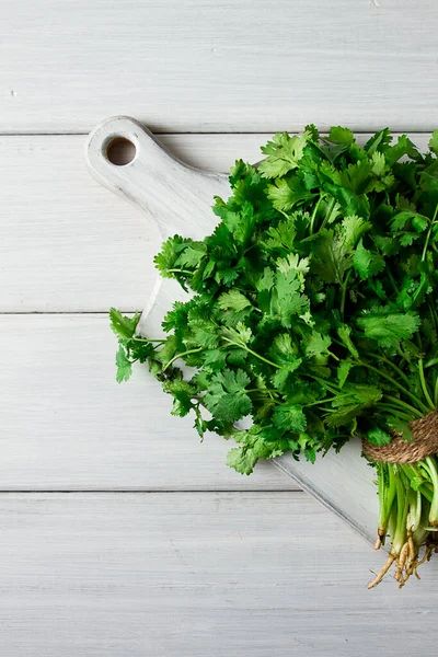 Bir grup taze Cilantro, beyaz ahşap bir masada, yakın plan, üst manzara, insan yok..