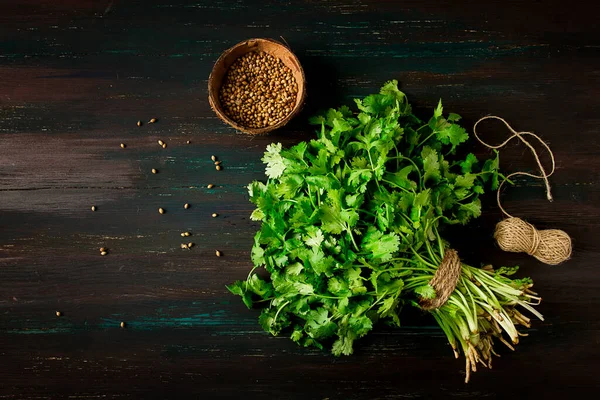 bunch of fresh Cilantro, coriander seeds, on a dark wooden table, close-up, top view, no people. food and drink,