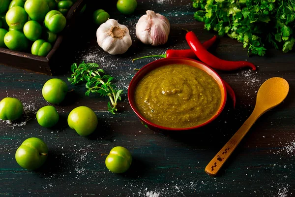 Tkemali sauce, traditional Georgian cuisine, green cherry plum, with ingredients for sauce, cilantro, mint, hot pepper, garlic, on a wooden table, close-up, rustic, food background, no people, selective focus, sauce, green sauce, tkemali, georgian cu