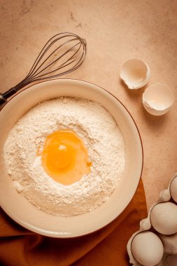 Yiyecek arka planı, konsept, buğday unlu tabak, kırık yumurta, çırpı, mutfak havlusu, bej bir masa, üst manzara, kırsal,