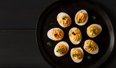 Haşlanmış yumurta sarısı, mayonez ile doldurulmuş, siyah tabakta, seçici odak, bulanık, yakın plan, insan yok.,