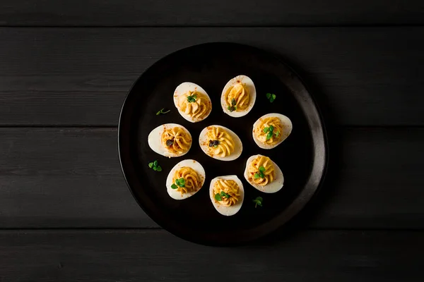 Boiled eggs stuffed with yolk with mayonnaise, on a black plate, selective focus, blurry, close-up, no people,