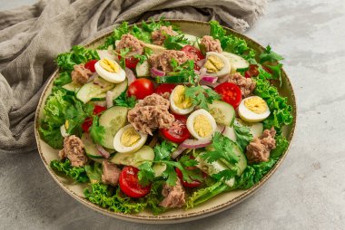 Ton balığı salatası, bıldırcın yumurtalı sebze salatası, marul, kırmızı soğan ve salatalık, açık gri bir masada, keto yemeği, yaşam tarzı, sağlıklı beslenme, seçici odaklanma, üst görünüm, insan yok.,