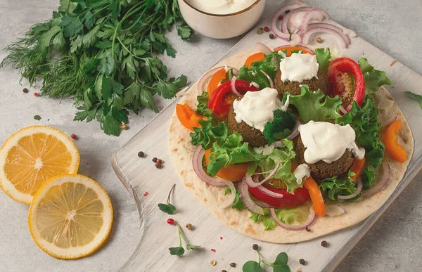 Tortilla with falafel and vegetable salad, white sauce, Arabic cuisine, top view, homemade, no people, vegetarian food,