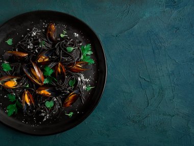 Spaghetti with black squid, black pasta, with boiled mussels, on a black plate, with parsley and parmesan cheese, close-up, selective focus, no people,
