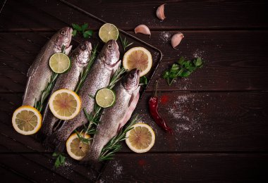 Raw rainbow trout, with lemon and herbs, on a wooden table, no people,