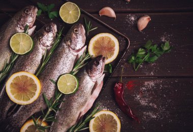 Raw rainbow trout, with lemon and herbs, on a wooden table, no people,