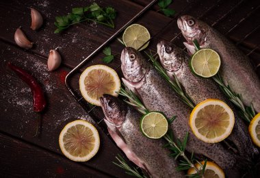 Raw rainbow trout, with lemon and herbs, on a wooden table, no people,