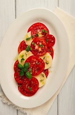Caprese salad, Italian traditional dish, tomatoes with mozzarella cheese, basil and spices, top view, no people,