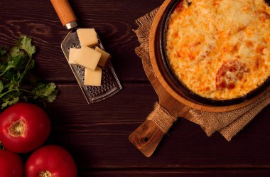 Baked tomatoes with Suluguni cheese , Ketsi in a clay pan , Georgian dish, homemade, top view, on a wooden table, no people,