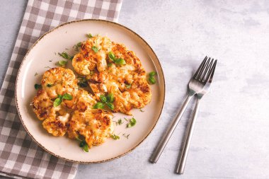 Biftek, karnabahar, peynirli, baharatlı, ev yapımı, açık gri bir masada, yakın çekim, üst görüş, seçici odak, insan yok.,