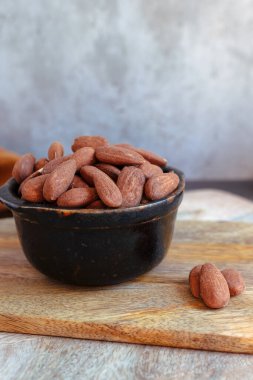 Tahtada fındık ve badem olan siyah kase.
