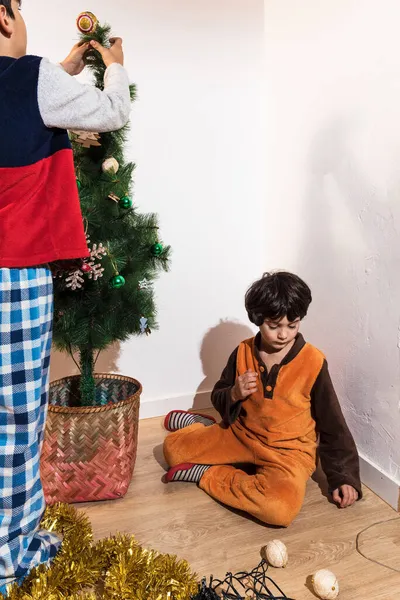 Dois irmãos jovens decoram a árvore de Natal em casa — Fotografia de Stock