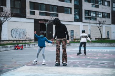 Genç beyaz anne kızına paten kaymayı öğretiyor.