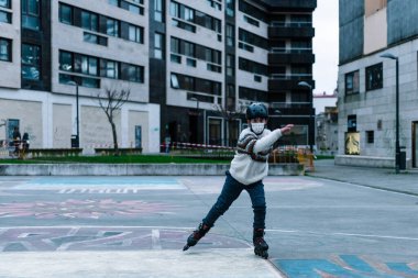 Beyaz çocuk şehir parkında paten çalışıyor.