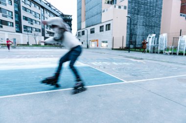 Beyaz çocuk şehir parkında paten çalışıyor.