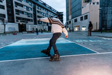 Beyaz çocuk şehir parkında paten çalışıyor.