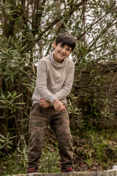 Um menino caucasiano na floresta com os braços cruzados dança e sorrindo — Fotografia de Stock