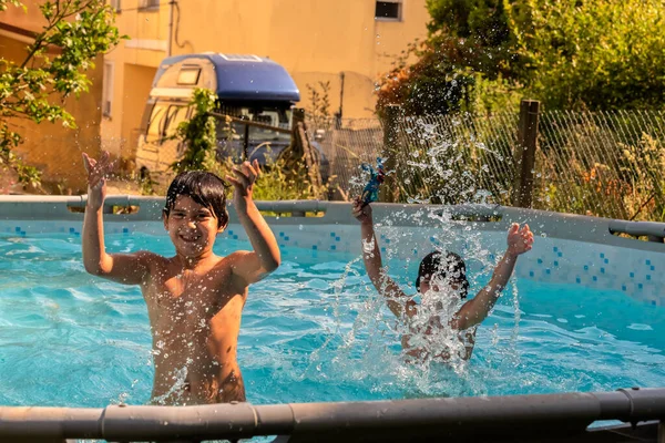 Caucasien frère et soeur jouer éclaboussures dans la piscine dans leur arrière-cour. — Photo