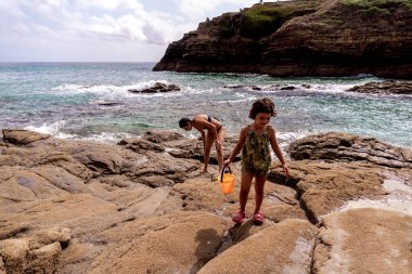 Kafkas kız annesiyle kayaların arasında bir kova suyla oynuyor.