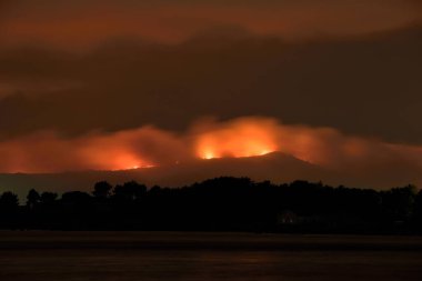 Illa de Arousa, Pontevedra, Spain. August 5, 2022: fire in Galicia the mountains burning in different spotlights tinged the night in Arosa Bay