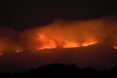 Illa de Arousa, Pontevedra, Spain. August 5, 2022: fire in Galicia the mountains burning in different spotlights tinged the night in Arosa Bay clipart
