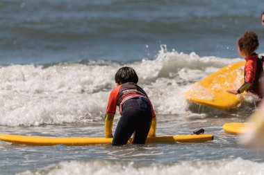 Aveiro, Portugal - August 19, 2022: A group of children practice with a surf instructor on the beach.