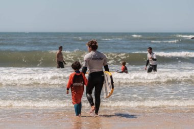 Aveiro, Portugal - August 19, 2022: A group of children practice with a surf instructor on the beach.