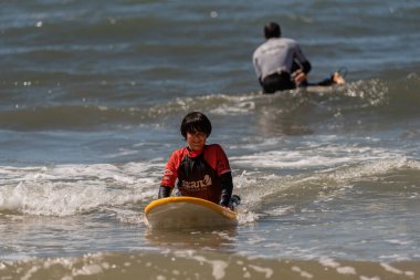 Aveiro, Portugal - August 19, 2022: A group of children practice with a surf instructor on the beach.