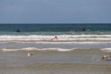 boy with orange equipment and bodyboard practices in the waves of Aveiro beach in summer