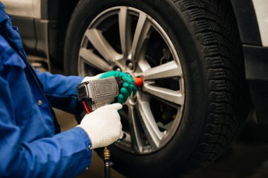 Otomobil tamircisi tekerlek dengeleyicisinde araba tekerleğini dengeler.