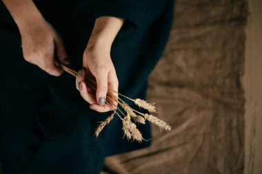Keten kumaştan bir arka planda ellerinde buğday başakları 