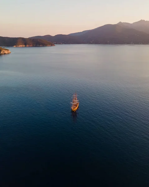 Aerial view of a pirate vessel sailing along the coast at sunset in Capo D'Enfola, Elba Island, Tuscany, Italy.