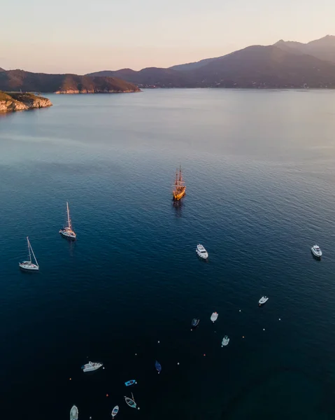 Aerial view of a pirate vessel sailing along the coast at sunset in Capo D\'Enfola, Elba Island, Tuscany, Italy.